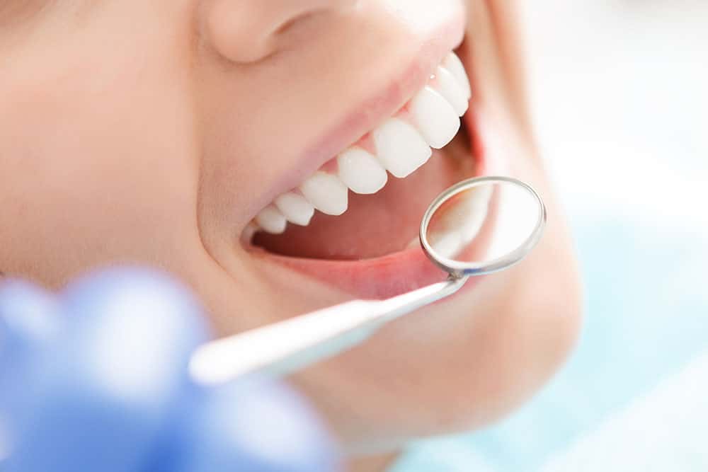 Woman smiling with dental tool near mouth