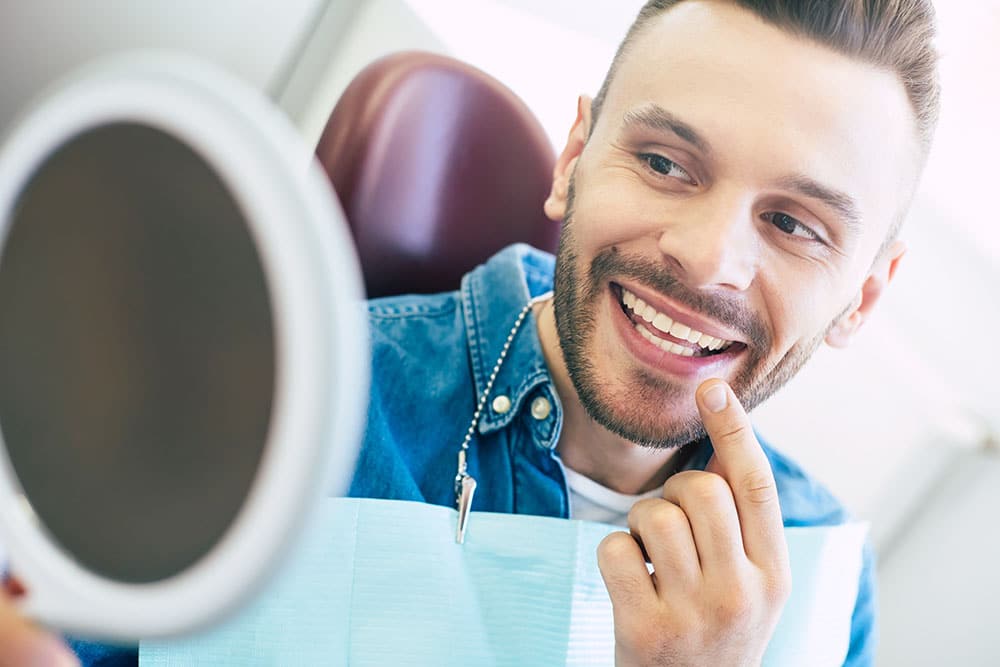 Man looking at his smile in the mirror