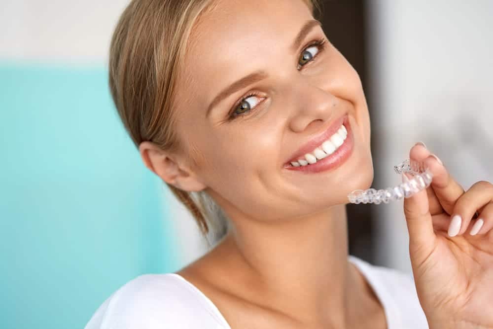 woman smiling with Invisalign tray